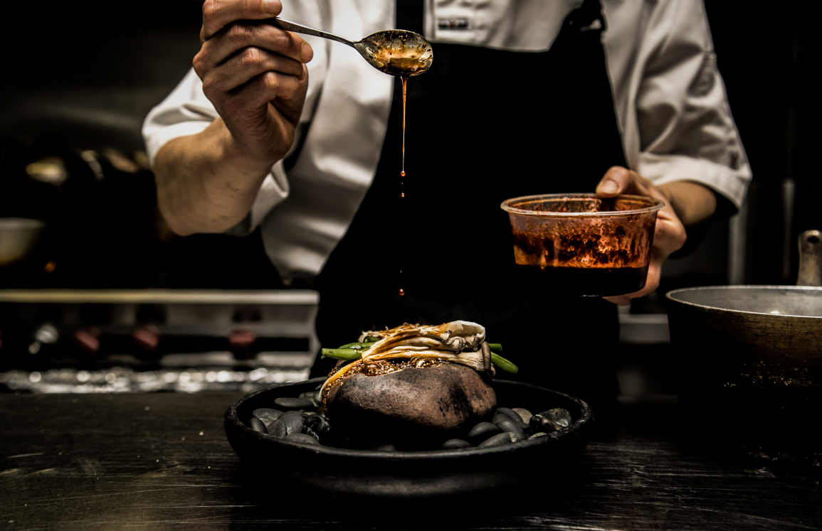 Chef plating a contemporary dish in moody restaurant lighting