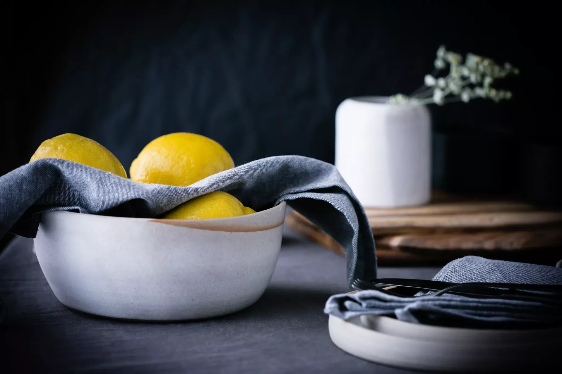 Lemons in a ceramic bowl on a dark wooden table