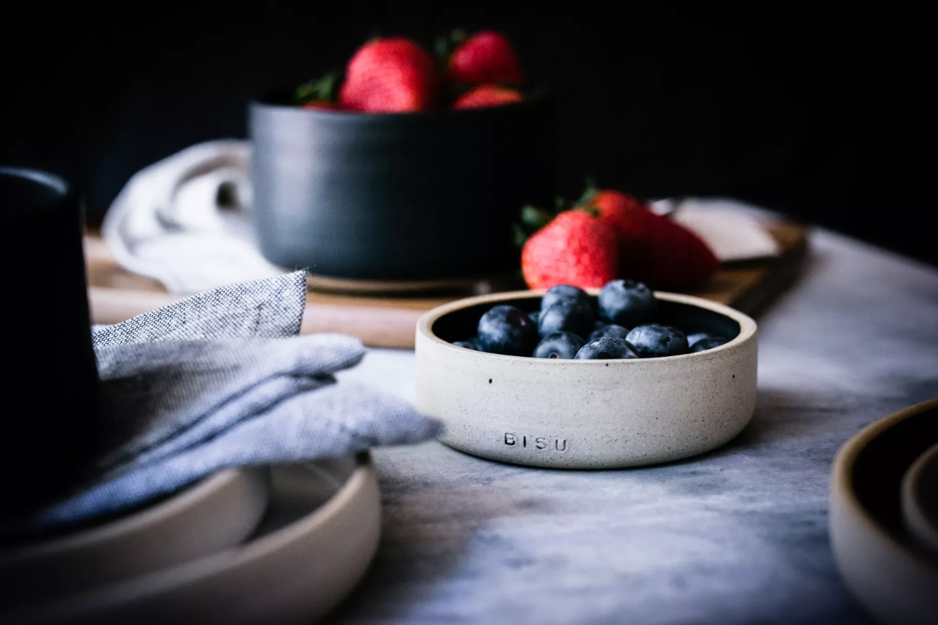 Berries in artisan ceramic bowls, marble surface