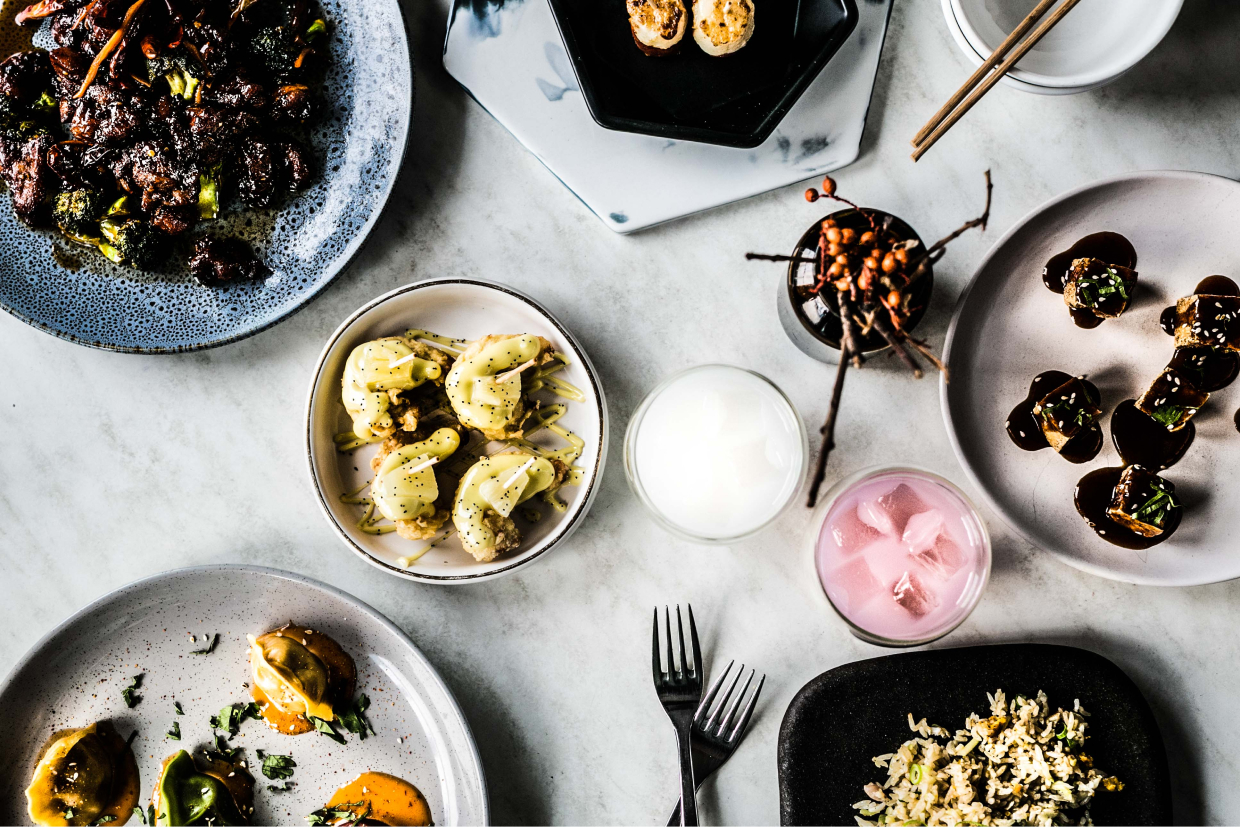 Overhead flatlay of Asian fusion sharing plates on marble